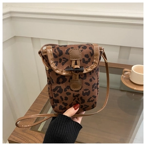 Detail of leopard print crossbody phone bag with horn buckle on a wooden table