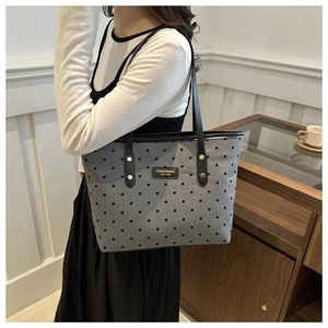 Detail of canvas tote bag with black polka dots and metal fashion logo label