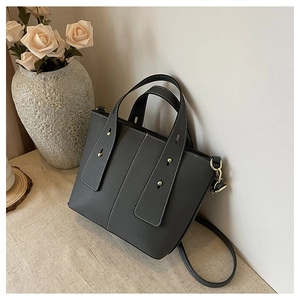 Detail of dark grey lychee textured handbag with white contrast stitching and gold rivets