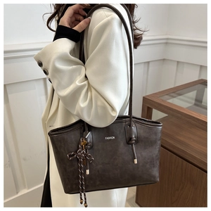 Detail of dark brown tote bag with white fashion print and knot shoulder strap detail
