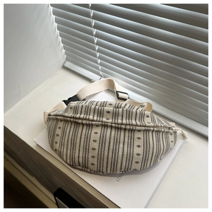 Detail of woven crossbody chest bag featuring black geometric patterns and buckle strap