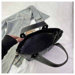 Detail of black tote bag interior with striped lining and contrast stitching finish