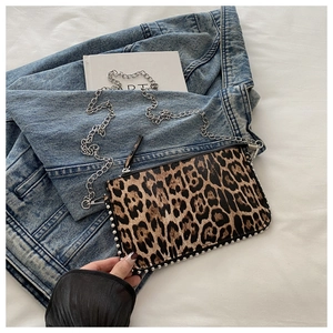 Close-up of leopard print crossbody bag with silver rivet studs and metal chain strap
