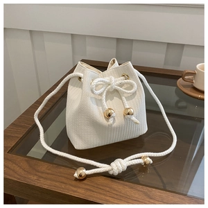 Detail of white woven bucket bag with thick cotton drawstrings and gold metallic beads