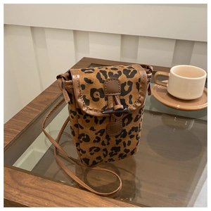 Detail of leopard print crossbody phone bag featuring horn toggle closure and brown leather trim