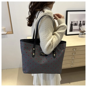 Close-up of gray canvas tote bag with red polka dots and reinforced black leather straps