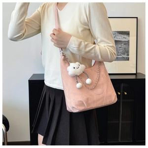 Detailed shot of pink crescent shoulder bag with silver chain and white plush charm
