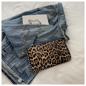 Close-up of leopard print crossbody bag with silver studs and metal chain strap