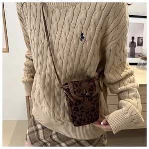 Close-up of leopard print phone bag featuring vintage buckle and textured brown trim