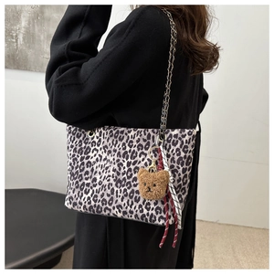 Dettaglio borsa shopper leopardata con ciondolo a orsetto e tracolla a catena sulla modella
