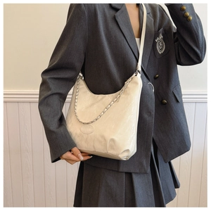 Detail of off-white hobo bag showing wrinkled texture and silver chain decoration