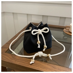 Detail of black knitted bucket bag with white drawstring and gold bead accents