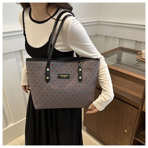 Détail du sac cabas gris imprimé cœur avec plaque logo noire et bandoulière élégante