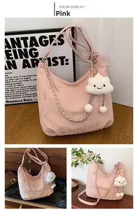 Detail of pink pleated crossbody bag with wide strap, silver chain, and plush cloud charm