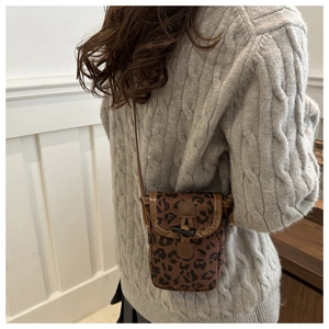 Detail of leopard print crossbody phone bag with horn buckle and leather trim