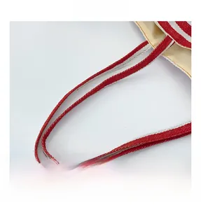 Detailed close-up of woven red and white fabric handle on a stylish autumn tote bag