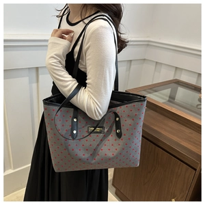 Detail of the gray tote bag with red heart pattern and black leather brand tag