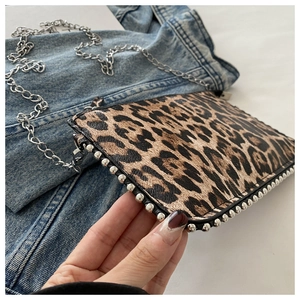 Detail of leopard print crossbody bag with silver rivet edges and metal chain strap