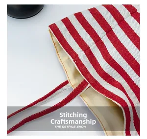 Close-up of the reinforced stitching and red-white striped fabric texture on the shoulder bag