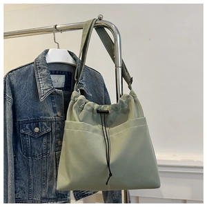 Detail view of light green oxford tote bag featuring a drawstring closure and outer pocket