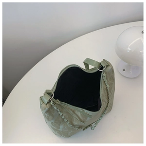 Detail of light green ruched shoulder bag showing silver chain strap and black interior