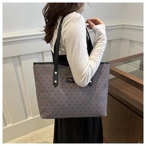 Detail of grey heart print tote bag with black handles and metal rivet reinforcement