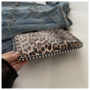 Close-up of leopard print crossbody bag with silver chain strap and metal rivet details