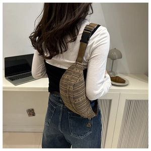 Detail of striped woven chest bag with adjustable brown strap and plastic buckle
