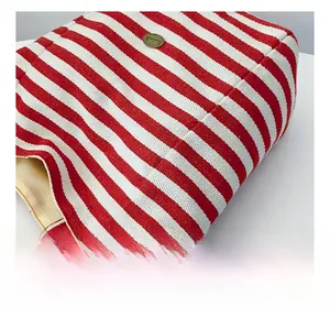 Macro shot of red and white herringbone canvas tote with vintage gold logo plate