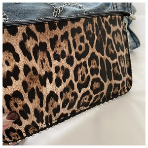 Close-up of leopard print bag with silver studs and metal chain over denim fabric