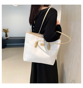 Close-up of white tote bag featuring vertical striped texture and brand logo detail