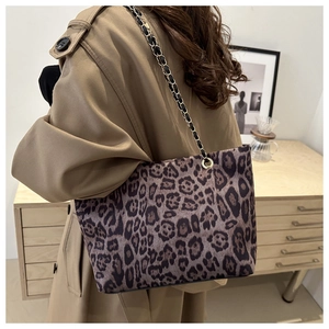 Borsa tote leopardata con tracolla a catena dorata indossata su un trench beige