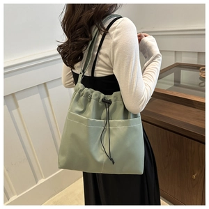 Detail of light green bucket bag with white stitching and adjustable drawstring closure