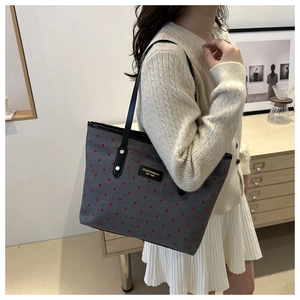 Star pattern gray tote bag with red polka dots and black straps on female model