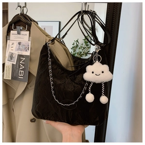 Detail of black pleated tote bag with silver chain and cute white cloud plush pendant