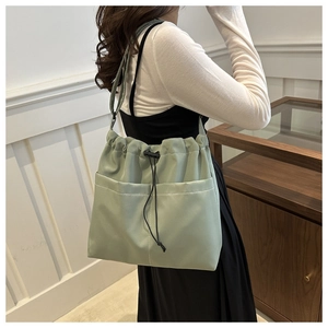 Macro detail of sage green nylon tote bag featuring spacious front pockets and drawstring