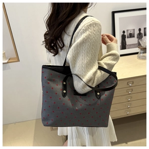 Detailed side view of large canvas tote bag with red polka dots and leather handles