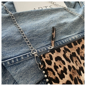 Detail of leopard print crossbody bag with silver stud trim and sleek metal chain strap