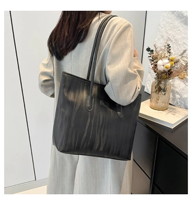 Side view of large black tote bag with zebra texture worn on shoulder in modern home