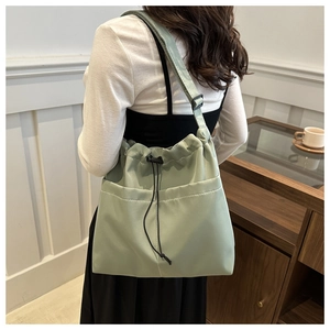Detail of light green nylon tote with drawstring closure and large front utility pockets