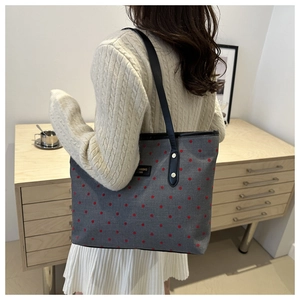 Vue détaillée du sac cabas en toile grise à pois rouges avec écusson en cuir noir gravé