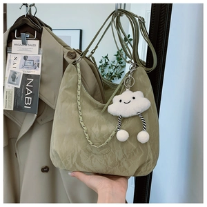 Detail of olive green crescent hobo bag with pleated texture and cloud plush charm