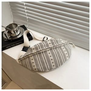 Detail of cream canvas chest bag with ethnic black stripes and adjustable wide strap