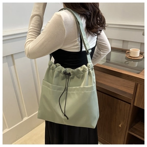 Detailed view of mint green drawstring tote bag with nylon texture and adjustable strap