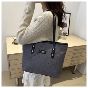 Detail of star print tote bag with red dots, black leather strap and fashion label