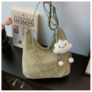 Detail of sage green textured handbag with braided strap and cloud plush charm decoration