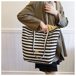 Macro detail of striped canvas tote with handmade yellow label and woven rope handles