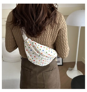 Detail of white canvas waist bag featuring colorful polka dots and adjustable strap