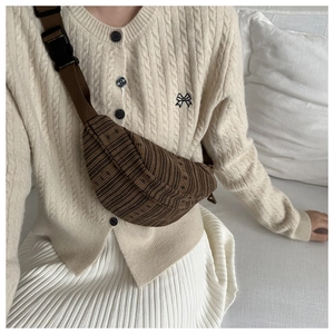 Detail of dark brown knitted crossbody bag showing 3D ribbed texture and adjustable strap