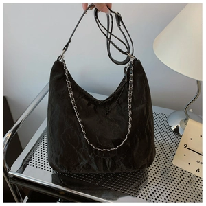 Detail of black pleated hobo bag featuring silver chain and wrinkled paper texture